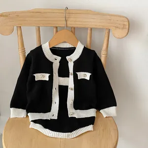 Detail der Baby-Strickjacke mit Kontrastbesatz und Metallknöpfen mit Schleifenprägung