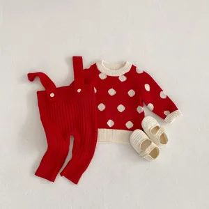 Detailed close-up of knit baby outfit with red polka dot sweater and ribbed suspender pants