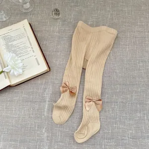 Knit baby leggings with vertical ribs and decorative satin bows in beige color