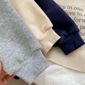Close-up of ribbed cuffs on children's cotton hoodies in grey, beige, and navy colors