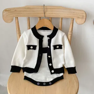 Details des Baby-Stricksets mit schwarz-weißem Kontrastrand und dekorativen Silberknöpfen