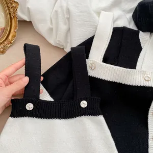 Detail der Strick-Baby-Strampler mit Schwarz-Weiß-Kontrast und goldenen Schleifenknöpfen
