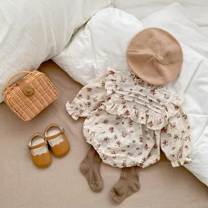 Detailed flat lay of floral long sleeve baby bodysuit with ruffle collar and accessories
