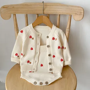 Detail of baby knit set featuring cute mushroom embroidery and rustic wooden buttons