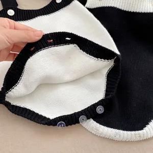 Gestrickter Baby-Strampler mit schwarz-weißem Farbblockdesign und Knopfleiste