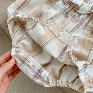 Detail of snap button crotch and elastic leg openings on baby floral plaid romper