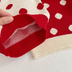 Close-up of flexible ribbed cuff on a red and white polka dot knitted baby sweater