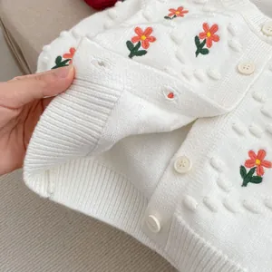 Detalle de cárdigan de punto para niña con bordado de flores y puntos con relieve