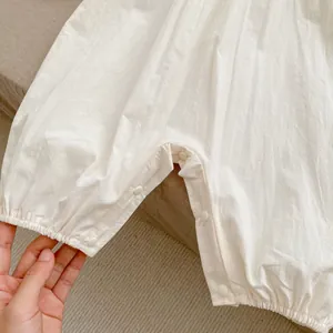 Détails des boutons-pression à l'entrejambe d'un barboteuse blanche pour bébé pour changer les couches