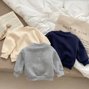 Detailed flat lay of three cotton sweatshirts in beige, grey, and navy for toddlers