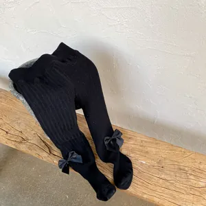 Close-up of black ribbed thermal leggings for girls featuring sweet satin bow details