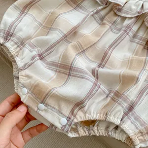 Detail of baby plaid romper featuring ruffle collar and bottom snap button closure