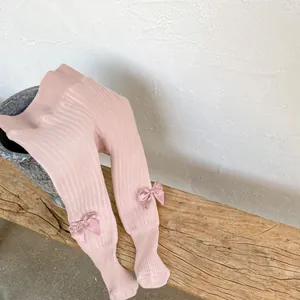 Detailed view of light pink ribbed winter tights for baby girls with cute satin bows