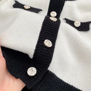 Gestrickte Baby-Strickjacke in Schwarz-Weiß-Kontrast mit goldenen Schleifenknöpfen für Mädchen