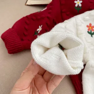 Detalle de la manga de cárdigan blanco con bordados florales coloridos y textura suave