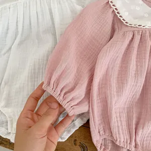 Detail of baby pink muslin bodysuit showing white Peter Pan collar with floral lace embroidery
