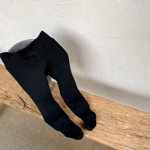Close-up of baby thick black knit leggings with elastic waist and ribbed texture details