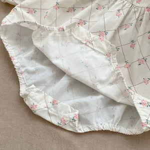 Close-up of baby romper bottom featuring pink floral print and white snap button closure