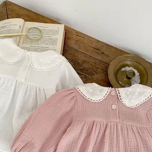 Detail of baby girl rompers showing vintage lace collars and organic cotton texture