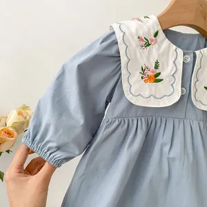Detail of baby girl dress featuring white embroidered collar with floral patterns