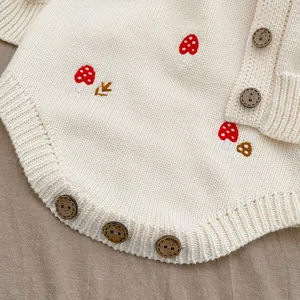 Detail of baby knit romper featuring mushroom embroidery and wooden texture buttons