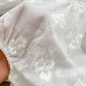 White baby romper with delicate floral embroidery and breathable cotton texture