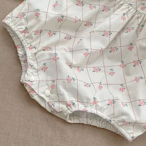 Detailed macro view of baby bodysuit bottom with pink floral print and snap fasteners