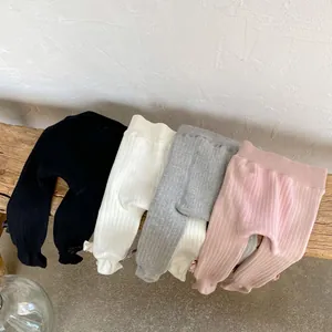 Close-up of knit baby leggings with bow accents and scalloped hems in various colors