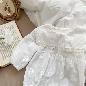 Detailed embroidery on white baby bodysuit with oversized lace collar and ruffles