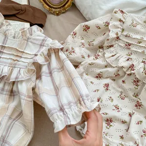 Detail of floral and plaid baby bodysuits with ruffled collars and breathable cotton fabric