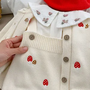 Detailed view of baby knit cardigan with cute mushroom embroidery and wooden buttons