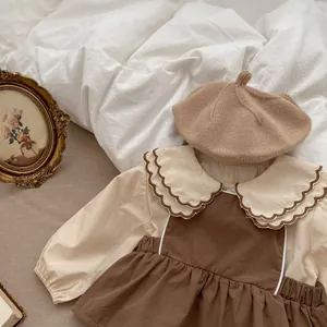 Detail eines Vintage-Babyoutfits mit beigem Rüschenkragenhemd und braunem Trägerkleid