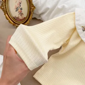 Gros plan du haut côtelé pour bébé avec broderie florale sur le col claudine blanc