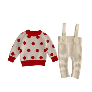 Baby knitwear set featuring a red polka dot sweater and beige ribbed suspender pants