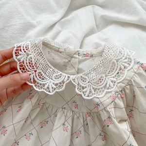 Detailed close-up of white crochet lace collar on floral cotton baby romper