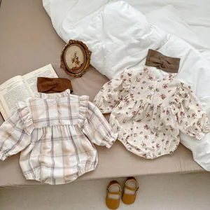 Flat lay of floral and plaid baby bodysuits with headbands and vintage leather shoes