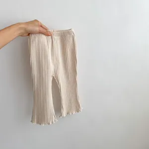 Close-up of beige ribbed knit texture and ruffled wave hem on infant flare leggings