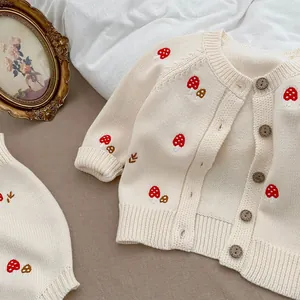 Detail of baby knit cardigan with red mushroom embroidery and wooden buttons