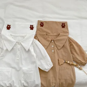 Dettaglio di tutine per neonati con ricamo a orsetto e colletto grande in bianco e kaki