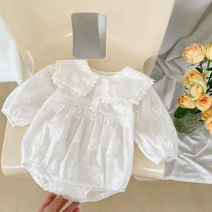 Close-up of white baby romper featuring delicate floral embroidery and lace collar detail