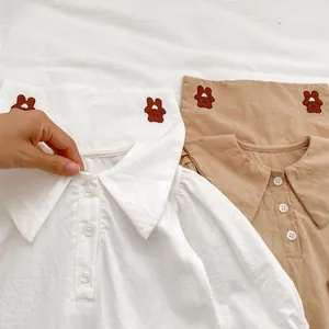 Dettaglio di camicia per neonato con colletto, ricamo orso e trama in cotone