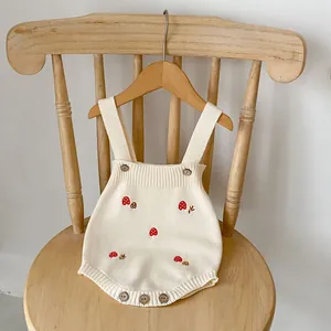 Detail of baby knit romper featuring mushroom embroidery and vintage wooden buttons