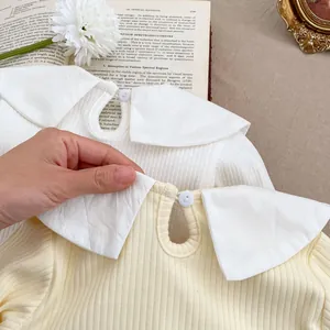 Détail du t-shirt côtelé pour bébé avec grand col Claudine et bouton de fermeture