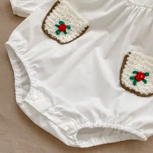 Detail of baby white cotton bodysuit with resin snap buttons and floral knit pocket