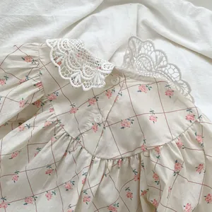 Close-up of baby romper with floral print and delicate white lace collar detail