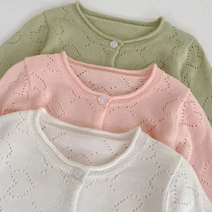 Detail of baby knit cardigan with hollow heart pattern in green, pink and cream white
