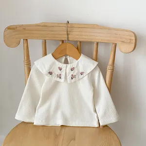 Détail du haut en coton pour bébé montrant la broderie florale sur le col Claudine et le tissu