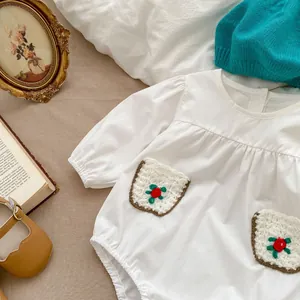 Close-up of baby romper showing embroidered pockets with floral design and soft fabric