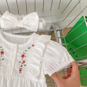 Detail of white cotton baby bodysuit with red flower embroidery and floral buttons