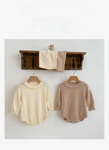 Close-up of knit baby romper with delicate hollow diamond patterns and ruffled collar
